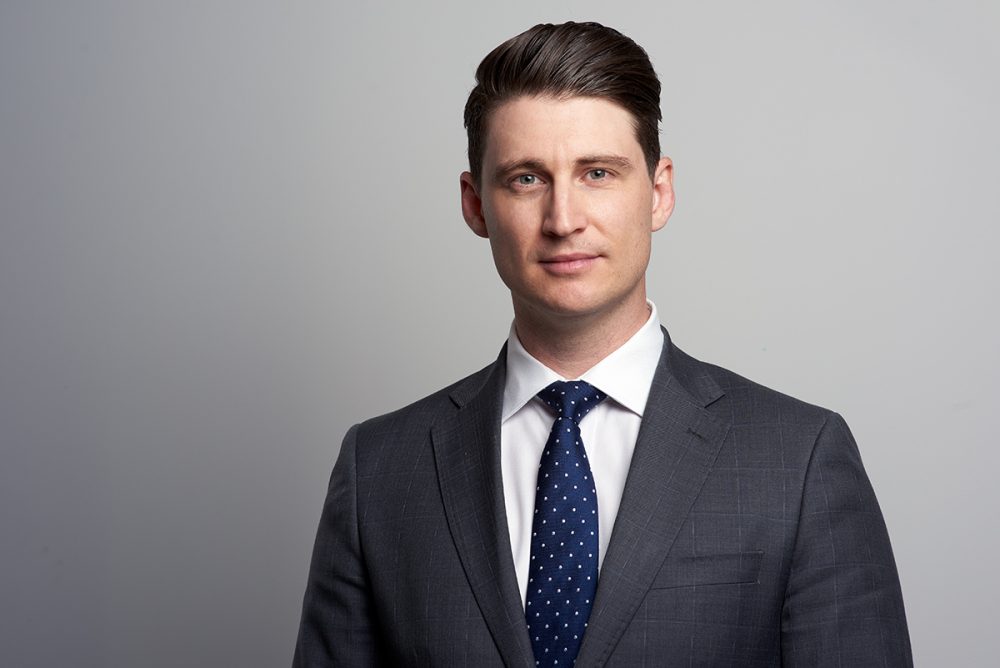 _ATL7848 Corporate type of portrait of a man standing. He is wearing a suit, white shirt and a tie. Studio photo against white background.